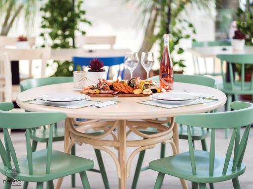 a table with a plate of food and wine glasses at Nayino Resort Hotel in Mamaia Nord