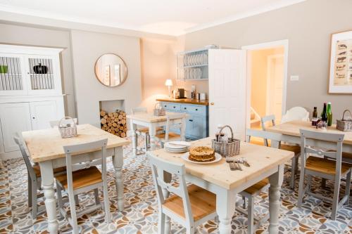 a dining room with tables and chairs and a kitchen at The Old Rectory in Campsea Ashe
