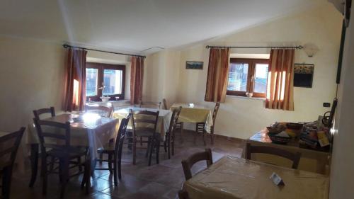 una sala da pranzo con tavoli, sedie e finestre di Affittacamere L'Airone a Villetta Barrea