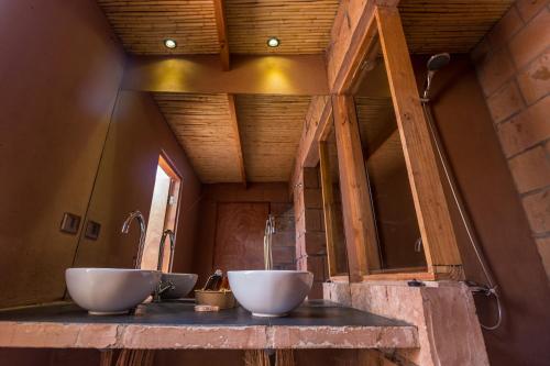 Baño con 2 lavabos blancos en una encimera en Eco-Lodge El Andinista, en San Pedro de Atacama