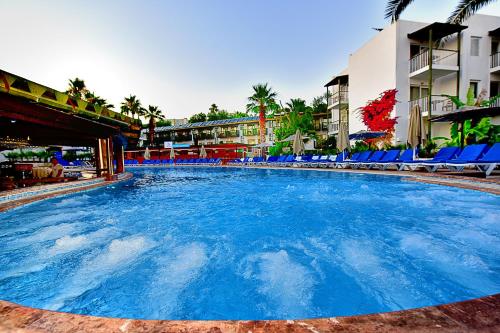 a large swimming pool with blue chairs and buildings at Parkim Ayaz Hotel in Gümbet