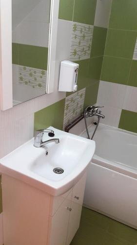 a bathroom with a sink and a tub and a mirror at Pensiune Restaurant la Pogace in Săpânța