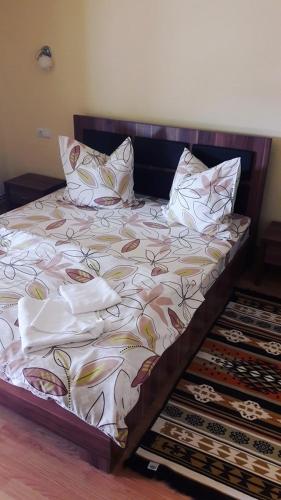a bed with pillows on it in a room at Pensiune Restaurant la Pogace in Săpânța