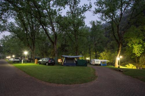 a campsite with a tent and cars parked in a park at Merry Pebbles Resort in Sabie