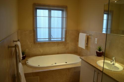 baño con bañera, lavabo y ventana en Pearl Valley-Golf Safari SA, en Paarl
