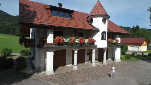 a person walking in front of a house with flowers at Pension Zenzlgut in Tiefgraben