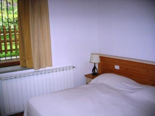 a white bedroom with a bed and a window at House Roberto by Holiday World in Castel del Piano