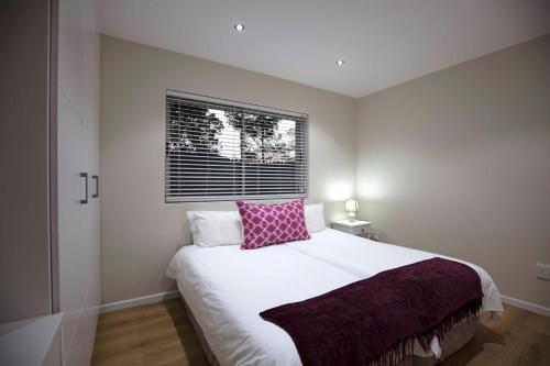 a bedroom with a large white bed with a pink pillow at No1 Sangaree in Plettenberg Bay