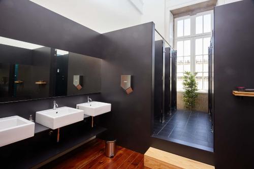 une salle de bain avec deux lavabos et un grand miroir dans l'établissement The Passenger Hostel, à Porto