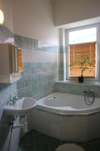 ein Bad mit einer Badewanne, einem Waschbecken und einem Fenster in der Unterkunft Apartmány Lestarka in Kořenov
