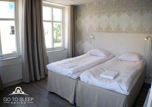 a bedroom with two beds with white sheets and two windows at Go to sleep Arvika in Arvika