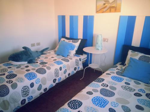 a bedroom with two beds with blue and white sheets at La casita de Esteban in Arrieta