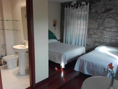 1 dormitorio con 2 camas, lavabo y espejo en Las Horas Perdidas, en Moscán