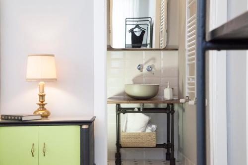 Naftalina Rooms في تيرمولي: حمام مع حوض وطاولة مع مصباح