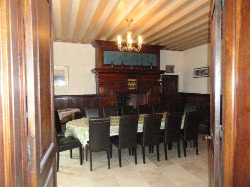 een eetkamer met een tafel, stoelen en een kroonluchter bij Château Ville Voisin in Augan