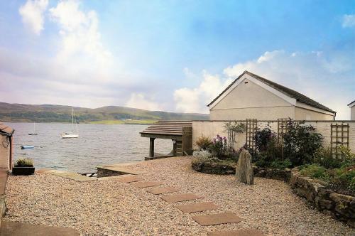 a building next to a body of water with a boat at Taigh na Mara in Kames