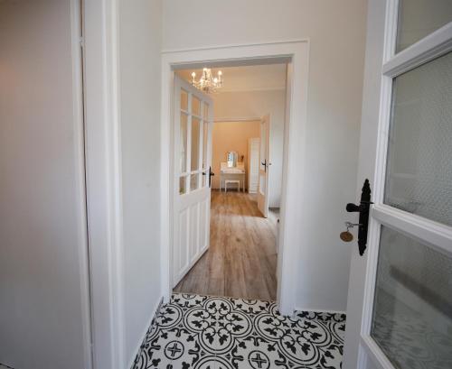 a hallway with a white door and a black and white floor at Öreg Malom Apartmanház in Bogács
