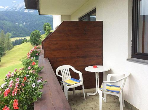 two chairs and a table on a balcony with flowers at Frühstückspension Rötelstein in Ramsau am Dachstein