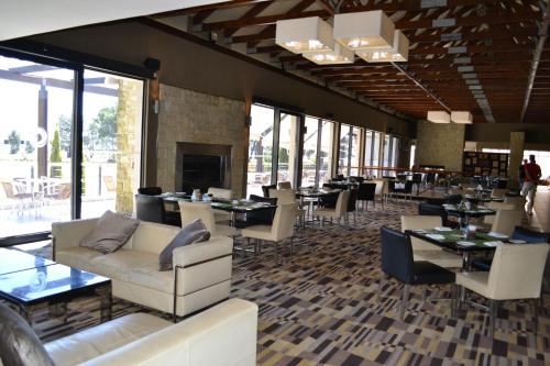 a restaurant with couches and tables and chairs and windows at Pearl Valley-Golf Safari SA in Paarl