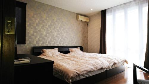 a bedroom with a bed and a desk and a window at Guest house Kotone KYOTO in Kyoto