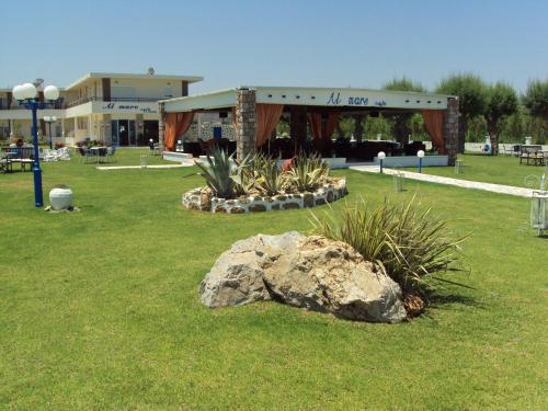 a park with a large rock in front of a building at Al Mare Apartments in Afantou