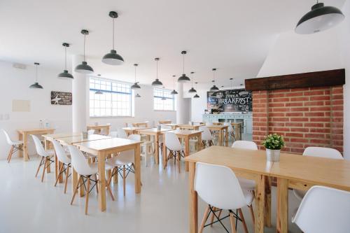 a dining room with wooden tables and white chairs at Zulla Nazaré`s Surf Village in Nazaré