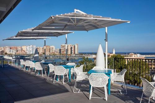 a row of tables and chairs under umbrellas on a roof at Room Mate Valeria in Málaga