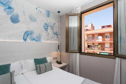 a bedroom with a white couch and a window at Hostal Operaramblas in Barcelona