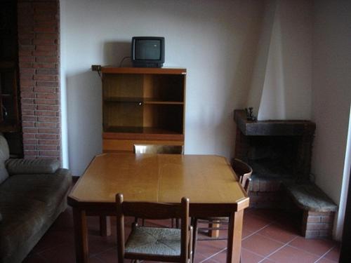 Habitación con mesa de madera y TV en un estante. en B&B Passo del Cerreto, en Cerreto Laghi