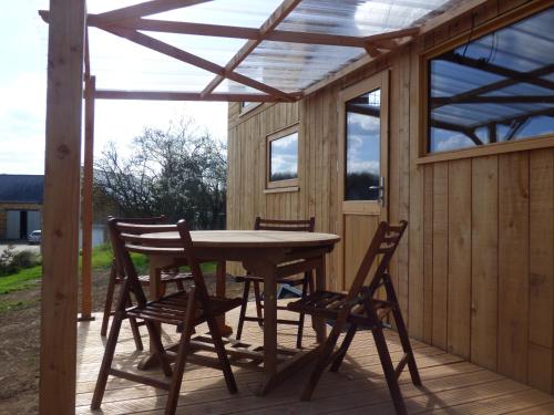 une terrasse en bois avec une table et des chaises dessus dans l'établissement le Vallon des 5 Roses, à Saint-Hilaire-du-Maine