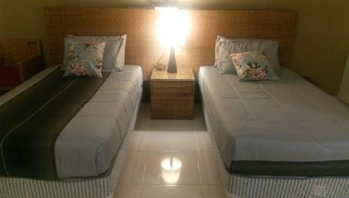 two beds in a room with a lamp on a table at ZamLan Gold Coast Morib Intl Resort - Studio in Banting