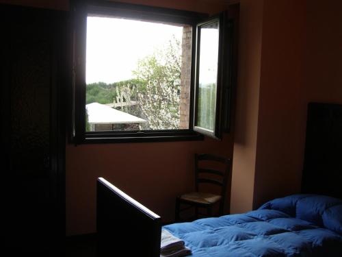 a bedroom with a window and a bed and a chair at B&B Le Grazie in Piaggine