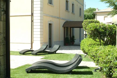 a group of benches in the grass in front of a building at Antica Stazione in Chiaramonte Gulfi