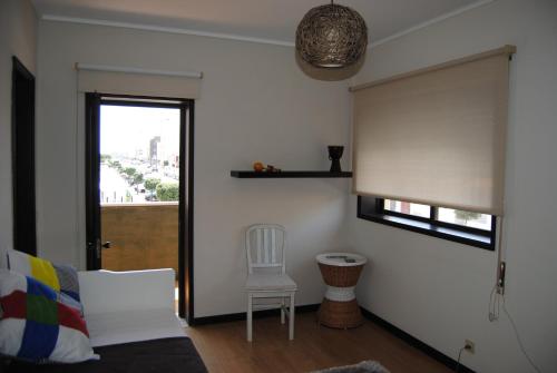 a living room with a window and a chair and a bed at Diamante Azul Barra Beach Apartment in Praia da Barra