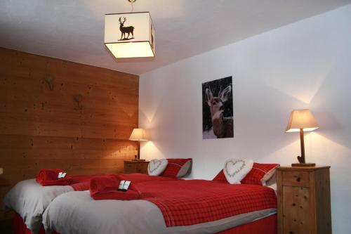 two beds in a room with red and white sheets at La Chanterelle - Mountain Lodge in La Côte dʼArbroz