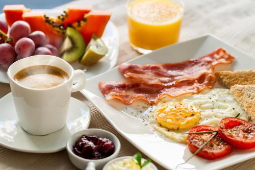 un piatto di prodotti per la colazione e una tazza di caffè di Hotel Theris a Megalochori (Isola di Agistri)