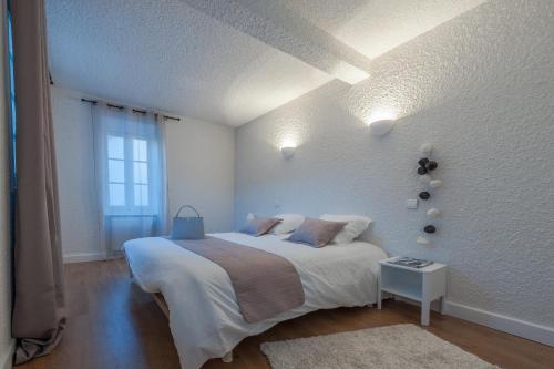 une chambre blanche avec un grand lit et une fenêtre dans l'établissement Cité Chic, à Carcassonne