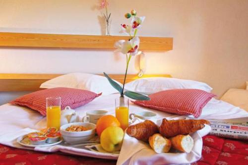 a breakfast tray on a bed with a tray of food at Hotel Grand Canyon du Verdon in Aiguines