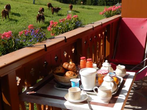 マニグードにあるLa Vieille Fermeの牛がいるバルコニーにティーセットが置かれたテーブル