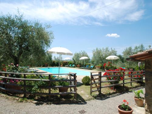 a fence next to a swimming pool with flowers and umbrellas at Il Poderino in Monteriggioni