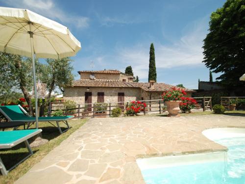 a patio with an umbrella and a house at Il Poderino in Monteriggioni