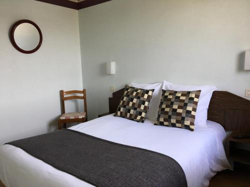 a bed with black and white pillows and a mirror at Hôtel Le Dauphin in Saint-Denis-de lʼHôtel