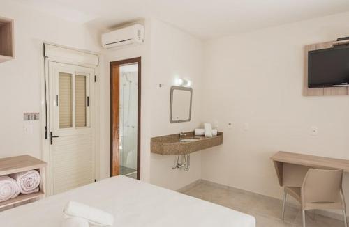 a white bedroom with a bed and a sink at Hotel Dois H in Joinville