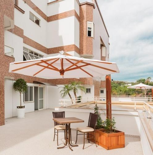 a patio with a table and a large umbrella at Hotel Dois H in Joinville