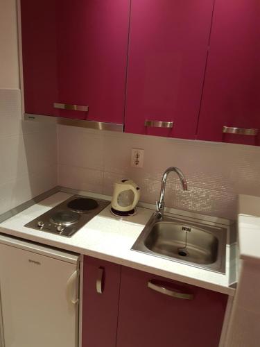 a small kitchen with a sink and purple cabinets at House Villa Roza in Tučepi