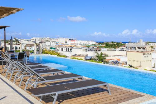 a swimming pool with lounge chairs and a view of a city at Papaya 15 Apartments in Playa del Carmen