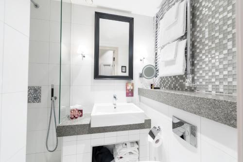 a white bathroom with a sink and a mirror at Hotel Kungsträdgården in Stockholm