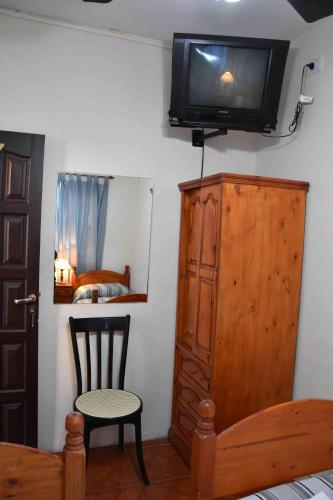 a bedroom with a tv on the wall and a chair at Residencial El Hogar in Salta