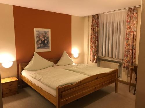 a bedroom with a bed with white sheets and a window at Gasthaus Metzgerei Pension Maßem in Schillingen