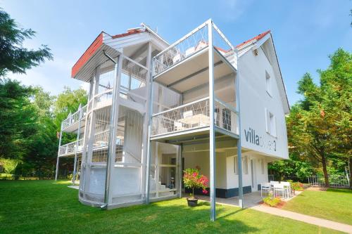 a white building with balconies on a lawn at Villa Oliver 3 Siófok in Siófok
